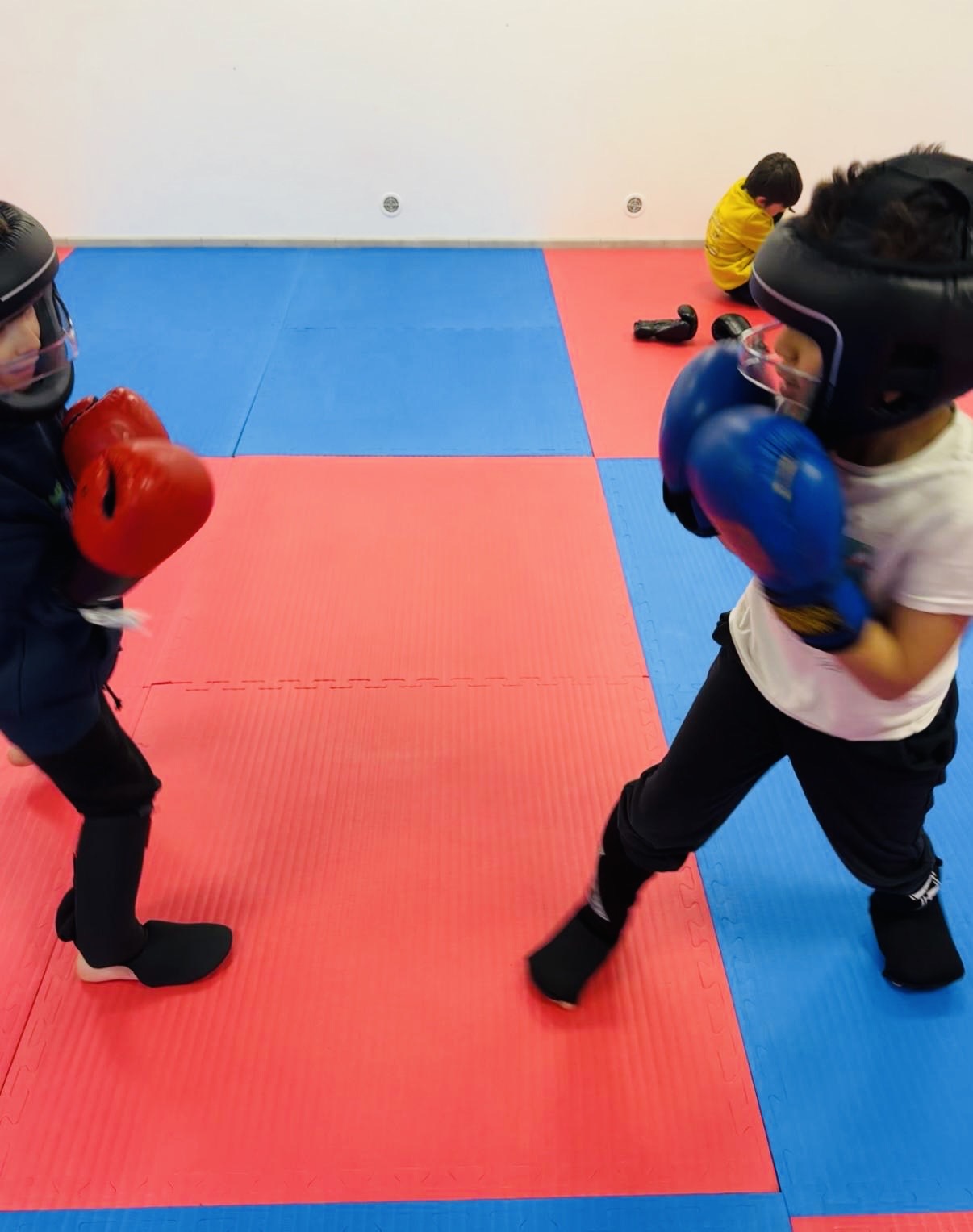 deux jeunes boxeurs du club en sparring, casques et gants